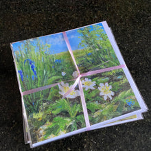 Set of  4 different greeting cards  and envelopes with woodland inspired designs tied together with a ribbon on a dark surface.