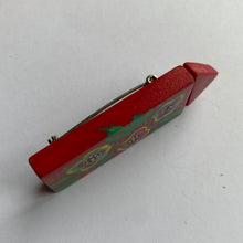 Handmade and painted red wooden brooch from the side