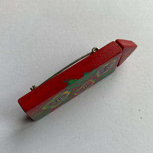 Handmade and painted red wooden brooch from the side