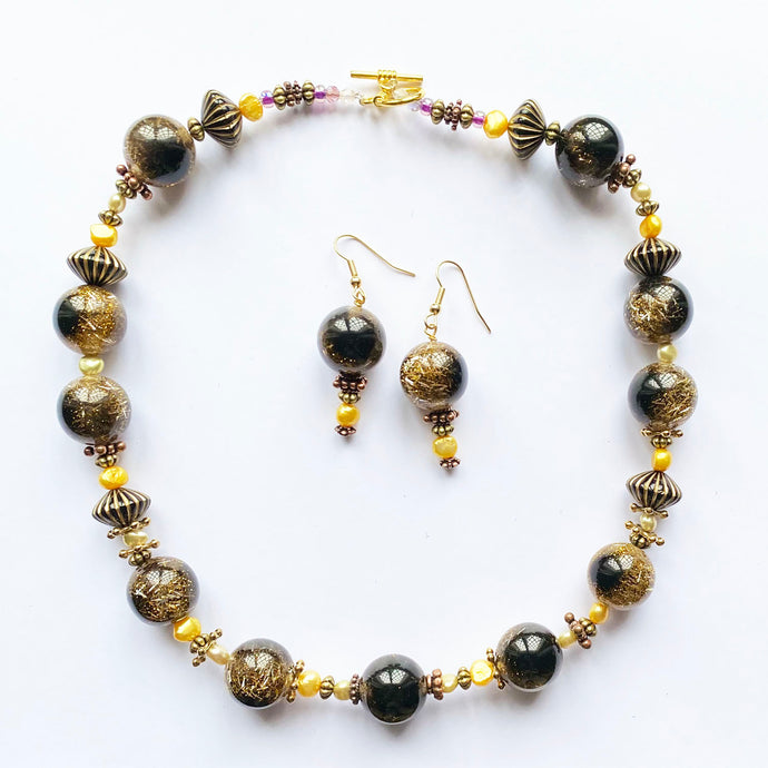 Artisan Unique  Necklace set, which mixes brown beads that have goldy sparkle inserts, with golden pearls and metal elements  with a gold plate metal toggle clasp. It comes with matching unique earrings on gold plate hoops.