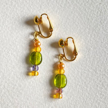 Pair of guilt plated clip earrings with 2 types of green beads, m iced with pearls on a white background