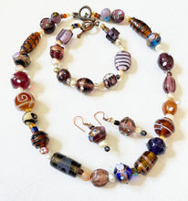 Beaded necklace and bracelet  made from randomly selected handmade glass beads with pearls, with similar earrings set on a white background