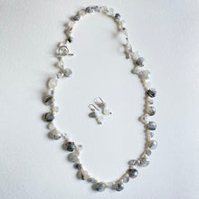 Extended necklace with grey and white cut stone beads mixed with pearls and matching earrings on a white background
